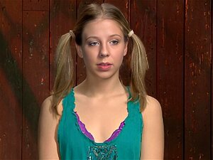 L'esclave blonde avec des couettes, Melody Jordan, est bâillonnée et attachée sur le sol en position arrière et se fait baiser les petits seins et fouetter le cul chaud par la lezdom Claire Adams dans un donjon